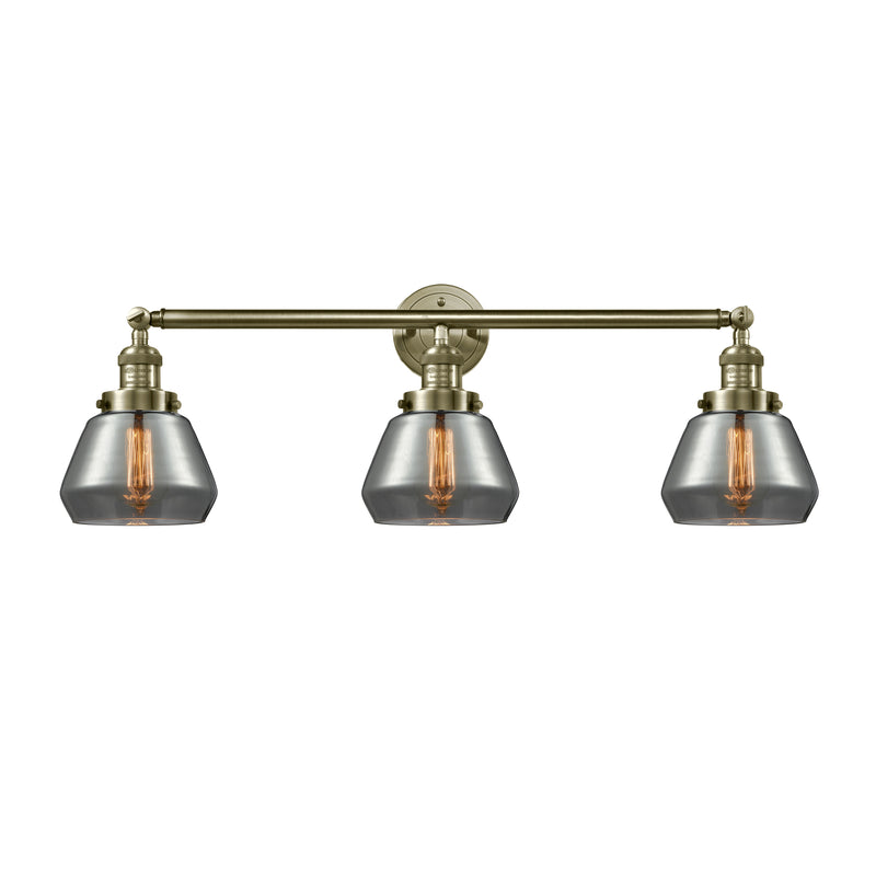 Fulton Bath Vanity Light shown in the Antique Brass finish with a Plated Smoke shade