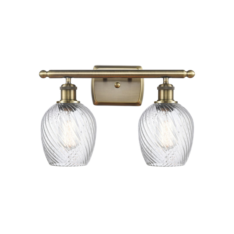 Salina Bath Vanity Light shown in the Antique Brass finish with a Clear Spiral Fluted shade